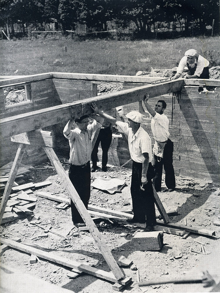 Black and white photograph of five men building the foundation of a house