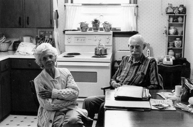 Black and white picture of 2 people at a table in a kitchen