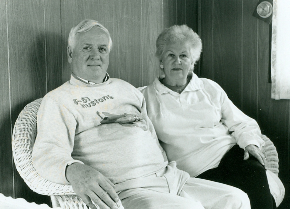 black and white photo of two people sitting on a wicker couch