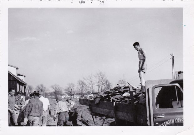Black and white photograph of men unloading a truck. At the top is typed APR 55