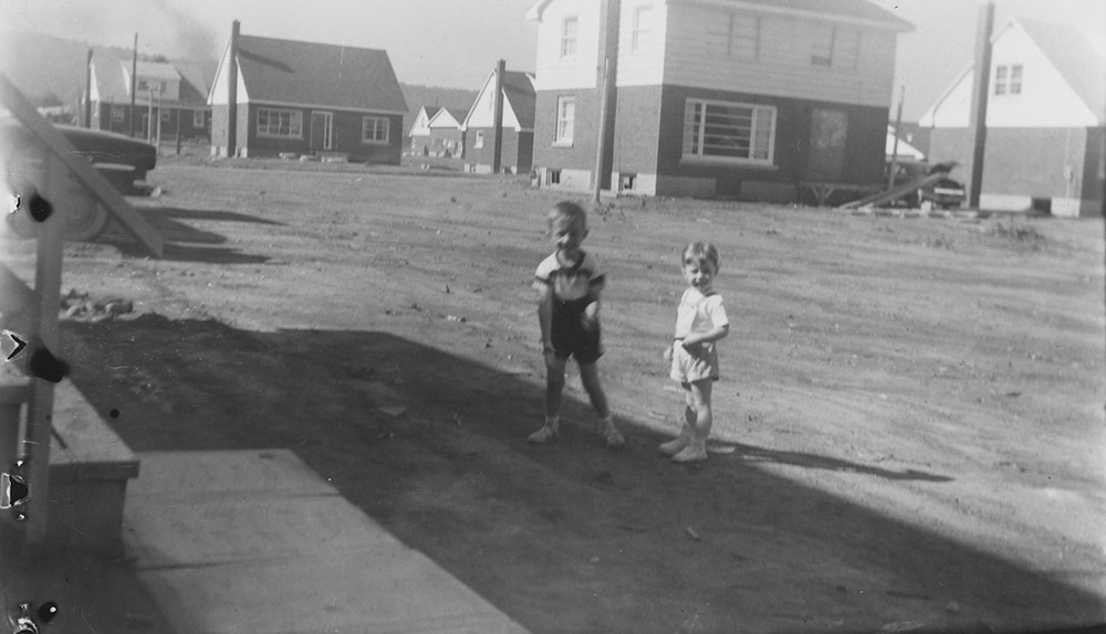 Photo noir et blanc de deux enfants à l’extérieur d’une maison.
