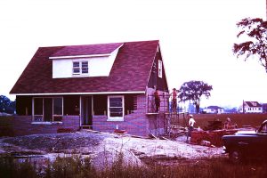 Colour photograph of men on scaffolding placing bricks on a house