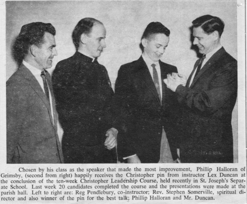 Black and white copy of a newspaper article of a young man getting an award with 3 men standing around. no title