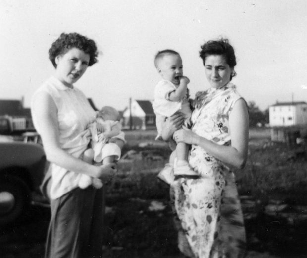 Black and white photograph of two women each carrying a child