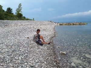 Colour picture of a person sitting on a stone beach