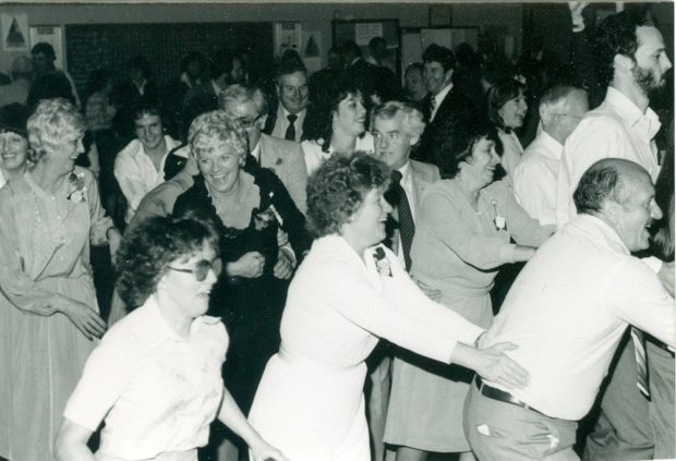 Black and white photograph of a group of men and women dancing and celebrating