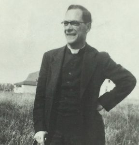 Photo noir et blanc d’un prêtre dans un champ.