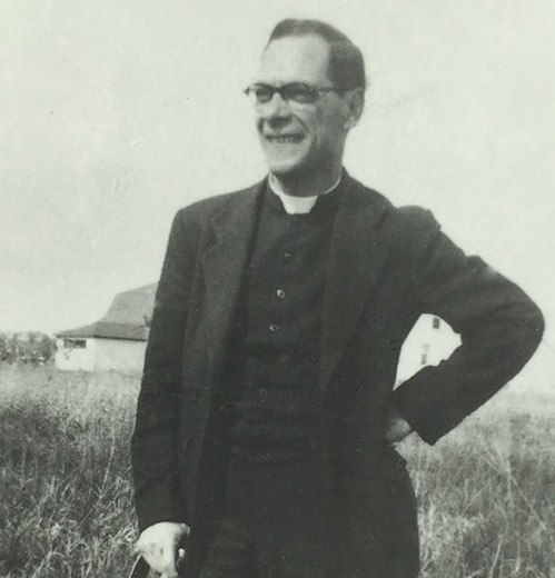 Black and white photograph of a Priest in a field