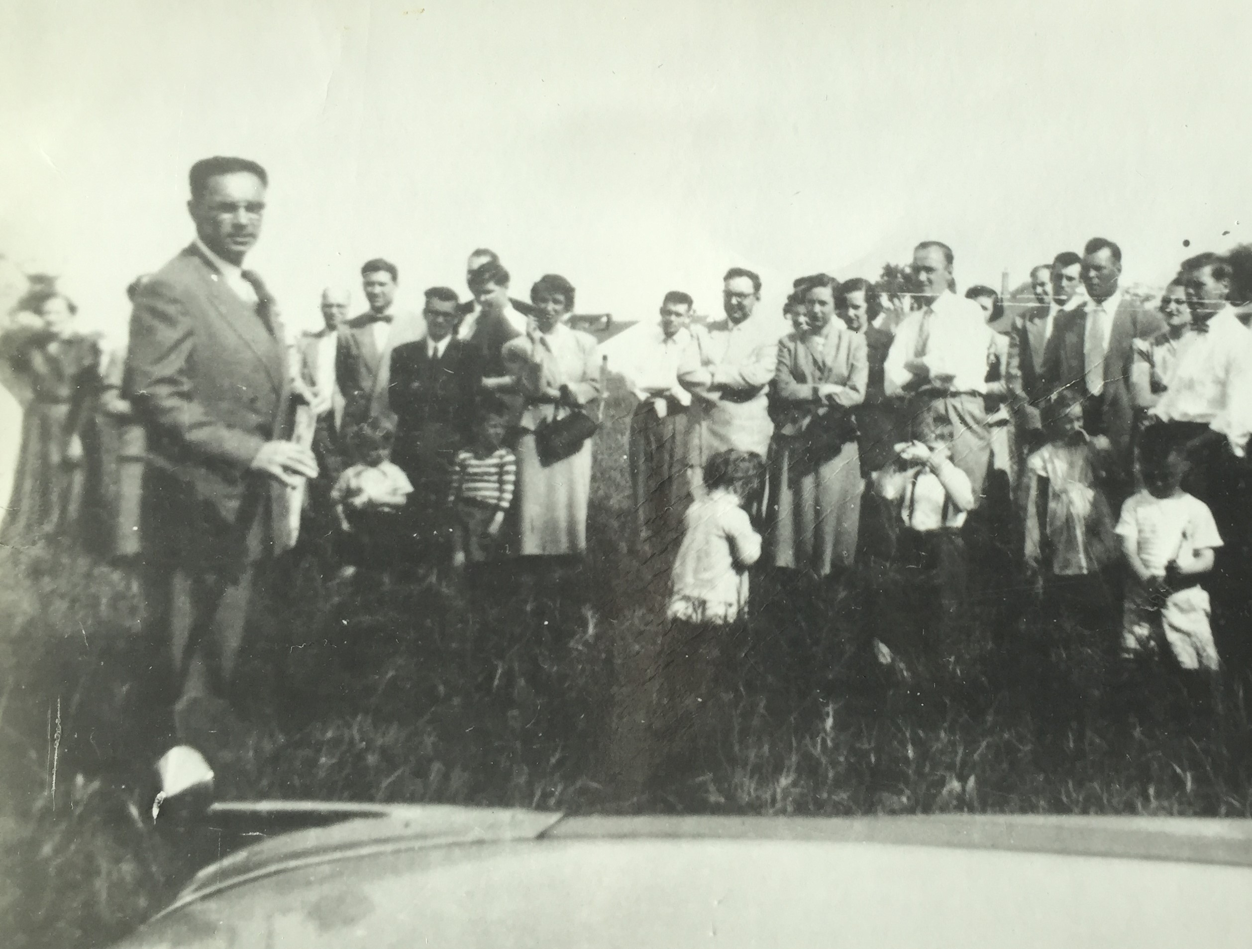 A group of adults and children in a field with a teacher