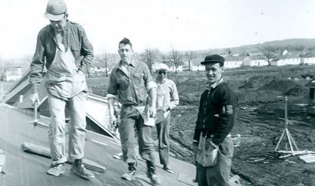 Black and white photograph of a group of four men on a roof
