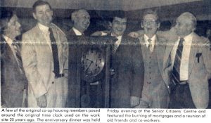 Article de presse, sans titre ; photo de 6 hommes près d’une horloge de pointage.