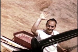 colour photograph of a man waving from a truck