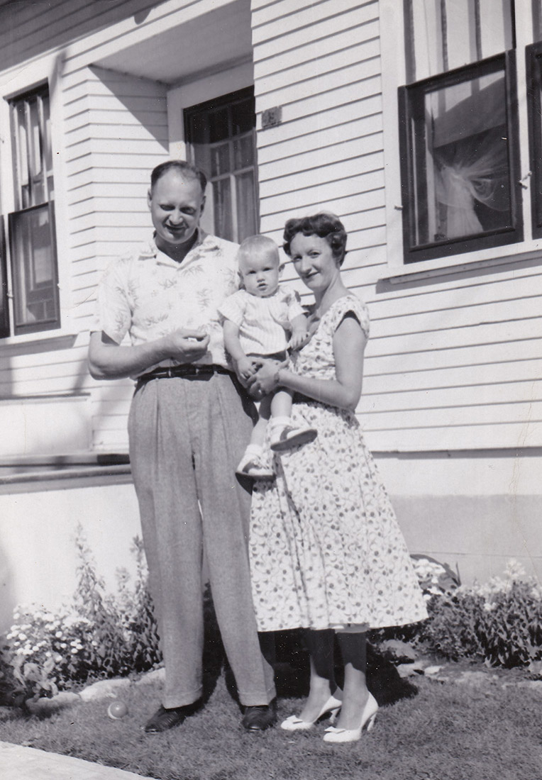Black and white photograph of a man, woman and small child in front of a house