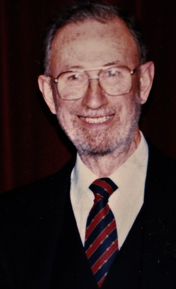 Colour photograph of a man in a suit wearing glasses
