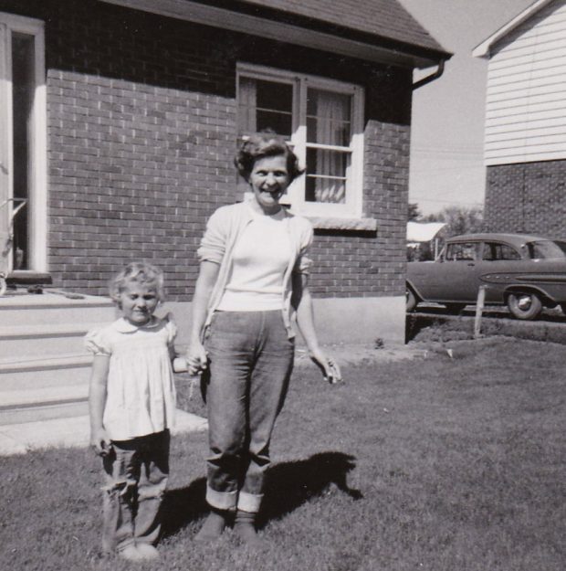 Black and white photograph of a woman and a child in front of a house