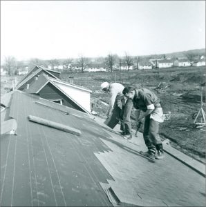 Black and white photograph of two men shingling a roof