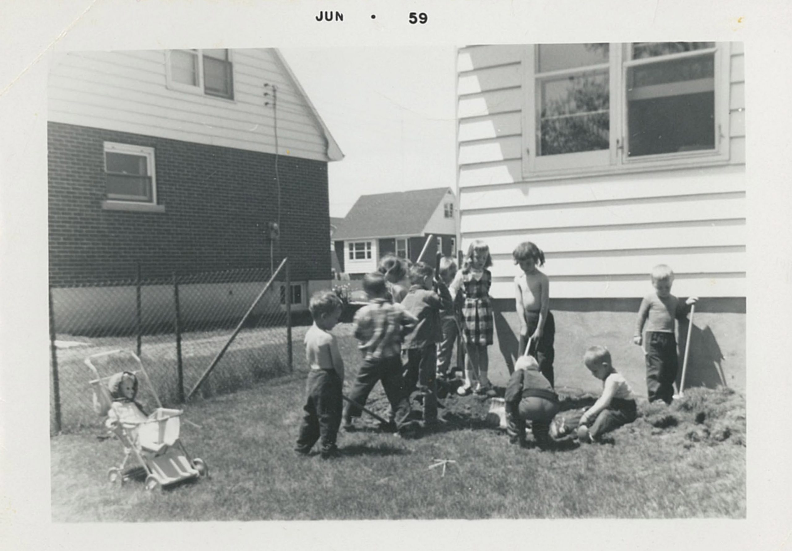 A black and white photograph of a group of children in a backyard. On the top there is typed 