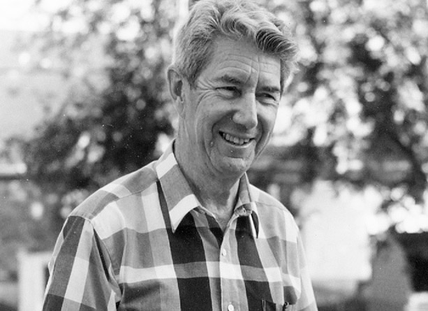 Black and white photograph of a man in a plaid shirt smiling