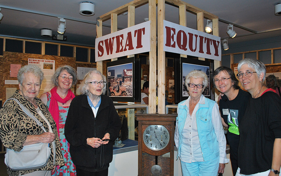 Colour photograph of a group of women at a museum exhibit "Sweat Equity"
