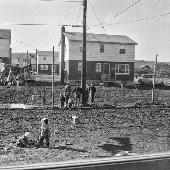 Black and white photograph of some people at a housing construction site