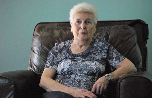 Colour photograph of a woman sitting in a chair in the centre of the photograph