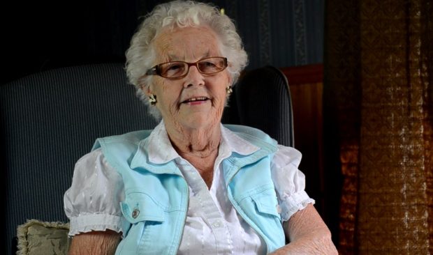 Colour photograph of a woman wearing glasses and a short sleeved white blouse