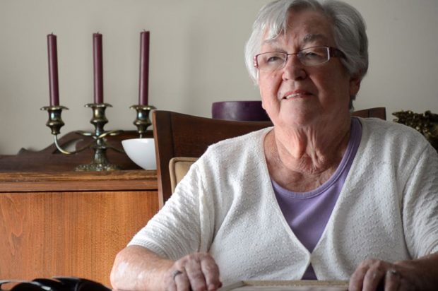 Colour close up photograph of a woman in a chair with candles in the background