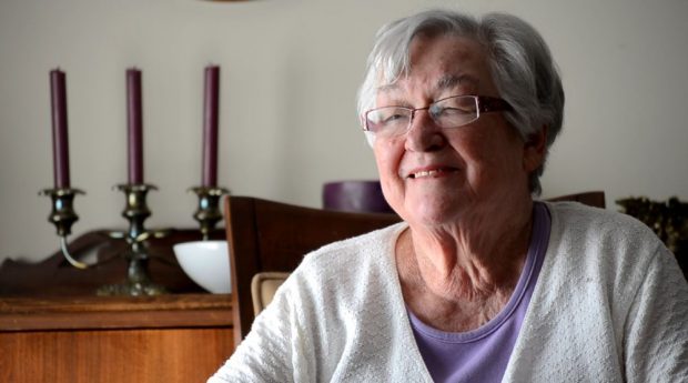 Colour close up photograph of a woman in a chair with candles in the background