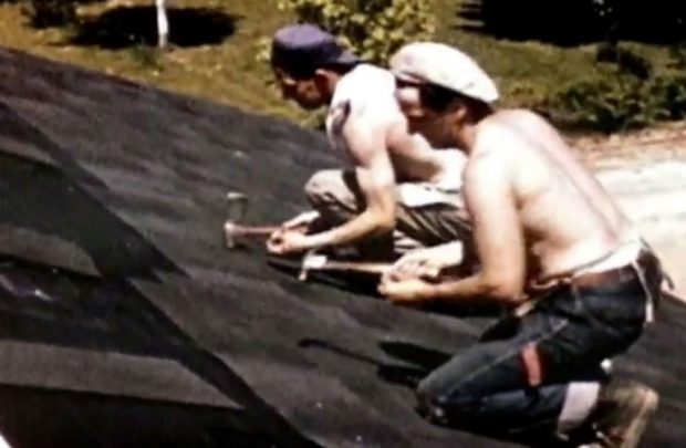 Colour photograph of two men shingling a roof one in a blue hat one in a white hat both shirtless