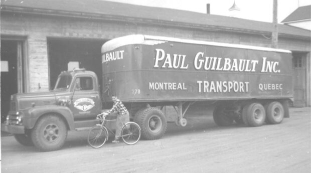 Black and white photo of a young cyclist next to a truck.