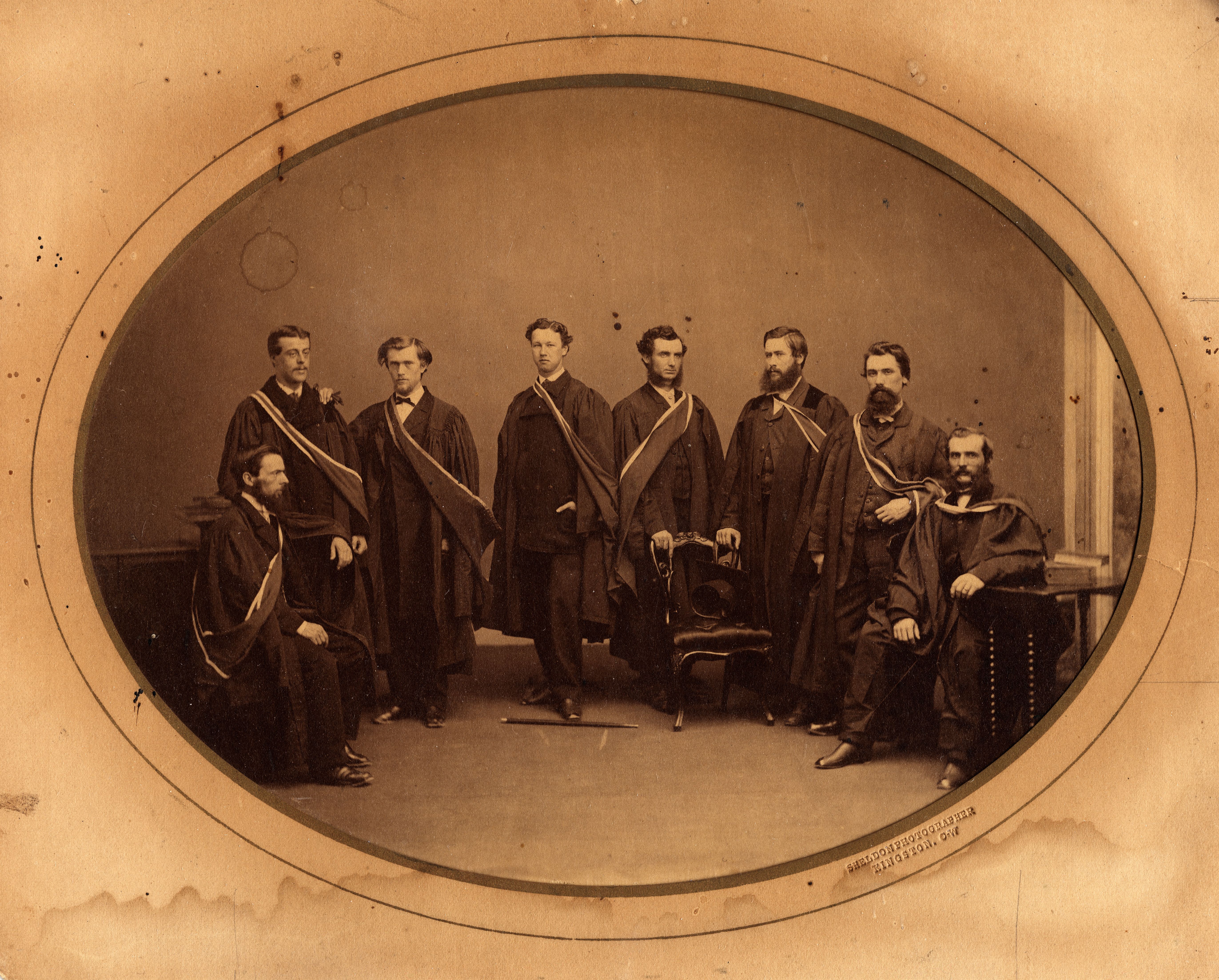 Period photograph of 8 Queen's University medical graduates in academic robes, 1865