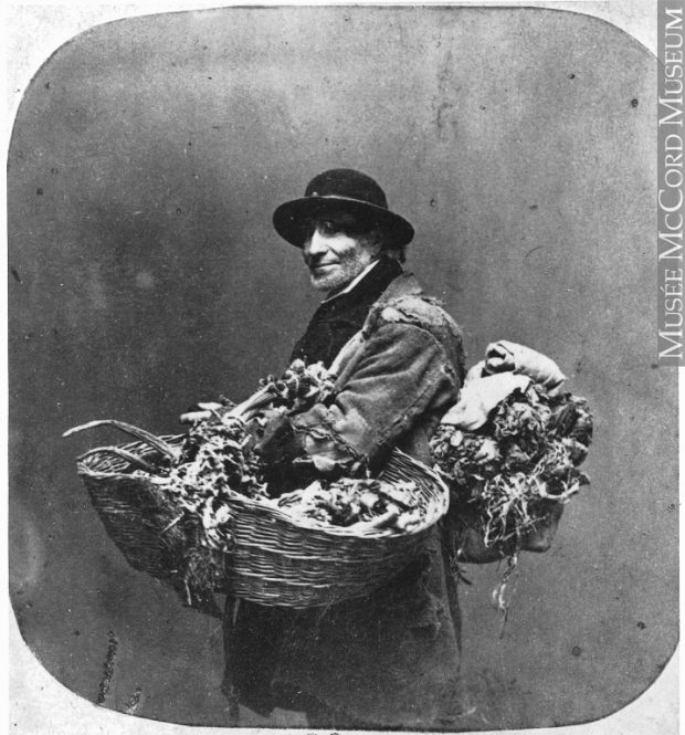 Period image of a man with a large roll of dried herbs on his back and a large basket of herbs on his arm circa 1859