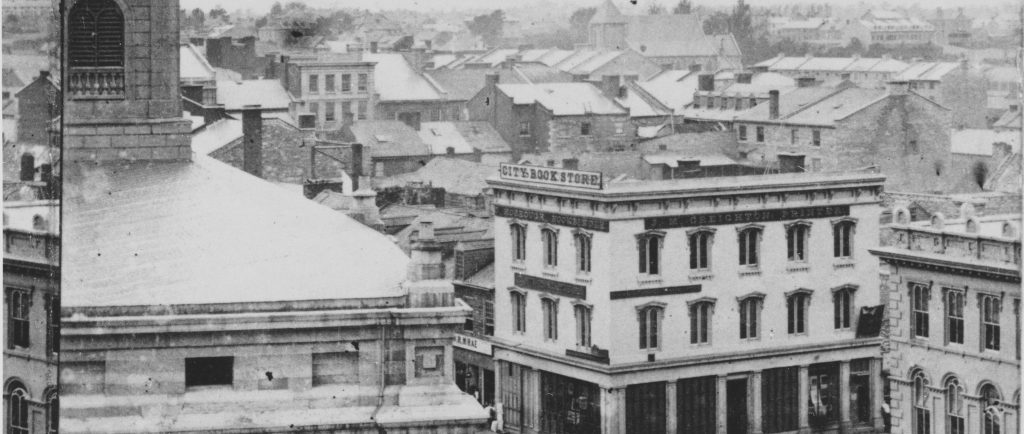 Streetscape photograph of Kingston in the 1860s with roads, sidewalks, and a number of buildings