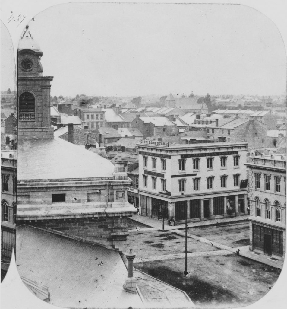 Streetscape photograph of Kingston in the 1860s with roads, sidewalks, and a number of buildings