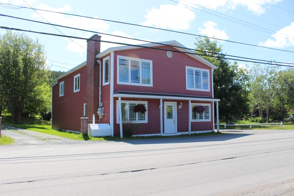 A colour photograph of a red building with a front porch.