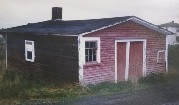 A color photograph of the exterior of Littlejohn's Forge, a single-story building painted red with white trim that appears to be weather-worn.