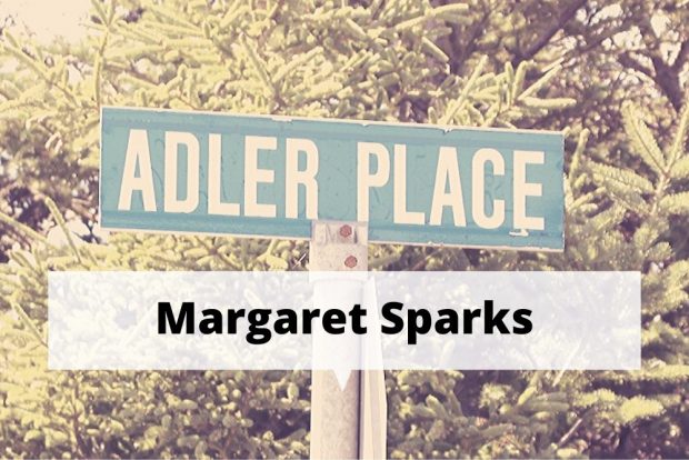 A colour photograph of the Adler Place street sign, atop a metal pole, with a spruce tree in the background.