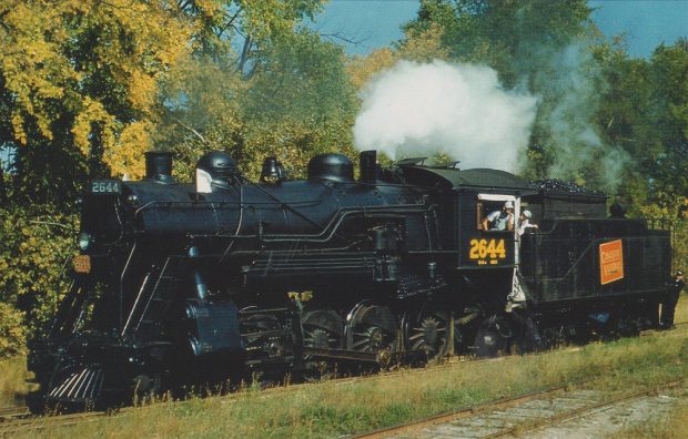 Colour image of steam locomotive with trees in background