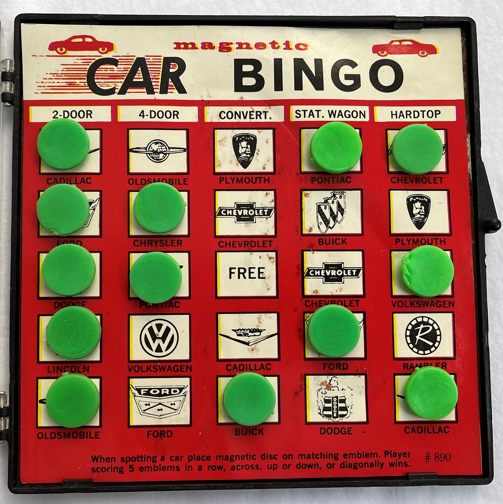 Colour image of plastic game board with green markers and paper surface showing various automotive logos