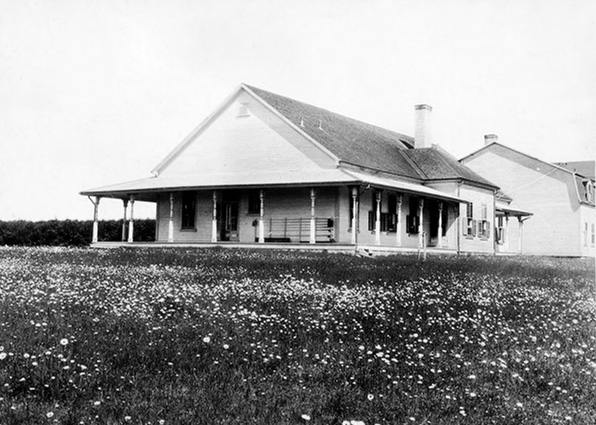 Silver print of the Estevan Lodge. You can see a Rod Rack to the right of the door and the centre of the building on the facade looking north to the field and the St. Lawrence River.