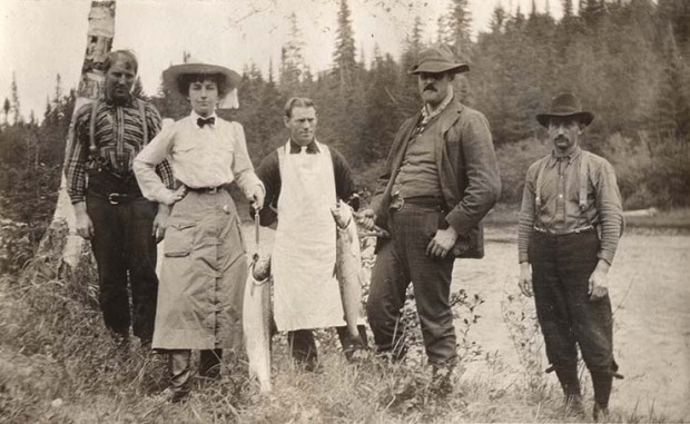 Silver print of Elsie Reford with four guides of the Tobique River showing two salmons.