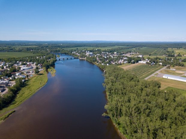 Aerial view colour photograph of Sainte-Anne River and both shores at municipality level and with both bridges.