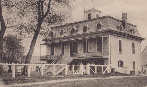 Black and white photograph of the new Sainte-Anne rectory where Father Laflèche lived with a sheet metal mansard roof brick front frontage porch and central staircase.
