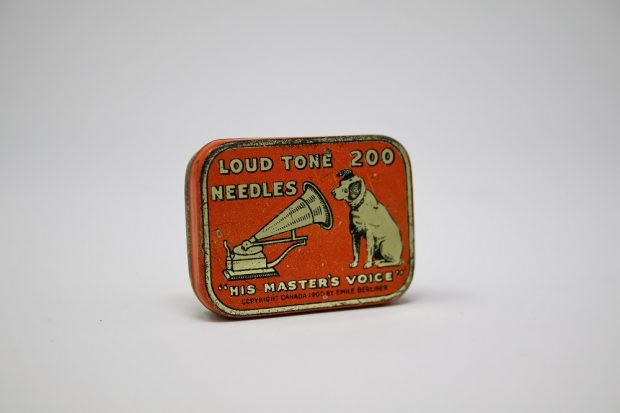 Orange rectangular metal box of 200 His master’s voice brand 200 gramophone needles patented by Emile Berliner. On the cover of the box there is an image of a gramophone and of a dog.