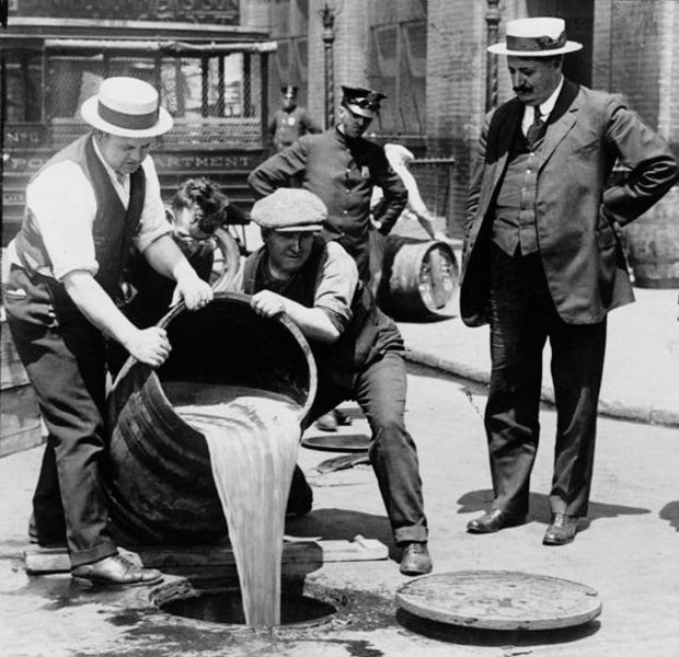 A watchful bailiff supervises workers as they pour the contents of a barrel down the sewer.