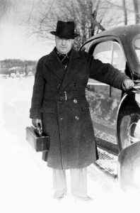Dr. Frank Lawless next to his car with his his medical kit in his hand.