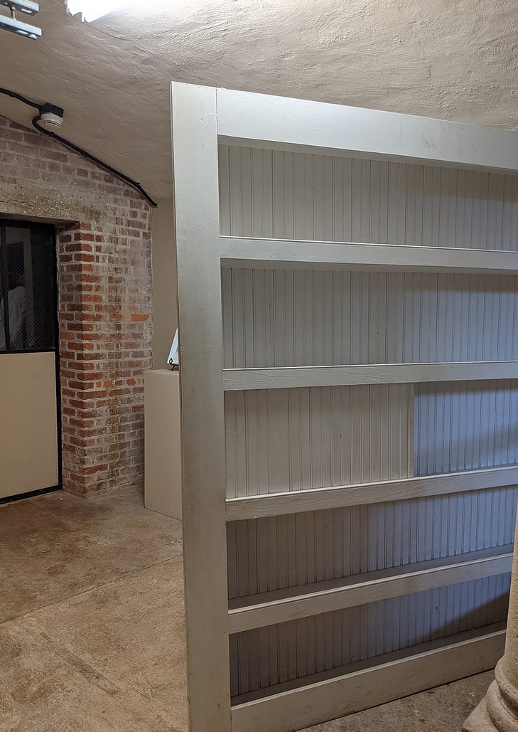 Shelves conceal the entrance to a room that will house a speakeasy.