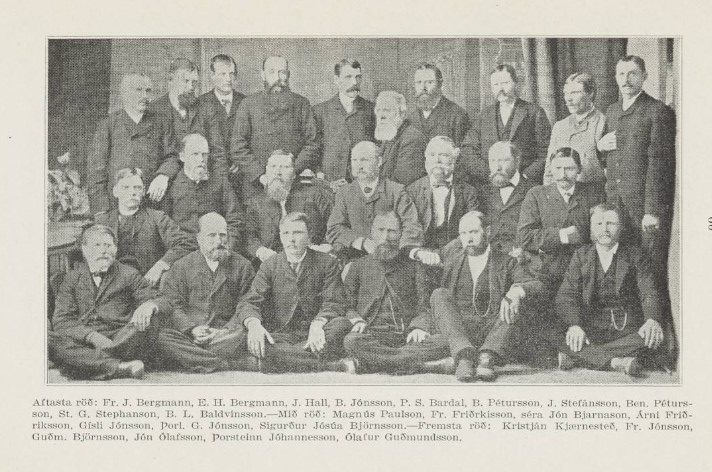 Svarthvít ljósmynd af hópi 30 manna raðaðra í þrjár raðir, klæddum formlegum 19. aldar jakkafötum. Sumir sitja með krosslagða fætur á gólfinu í fremstu röð, aðrir sitja á stólum í miðröð, og aftasta röðin stendur. Flestir eru með yfirvaraskegg eða skegg og hafa alvarlegt svipmót. Fyrir neðan myndina er áletrun á íslensku sem listar nöfn allra einstaklinganna, þar á meðal Fr. J. Bergmann, St. G. Stephanson og Ólafur Guðmundsson. Bakgrunnurinn sýnir einfalt gardínudraperí.