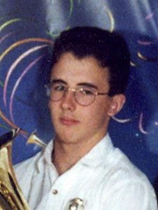 Colour photograph of François Moreau holding a brass instrument in his hands. He has glasses and is wearing a white shirt.