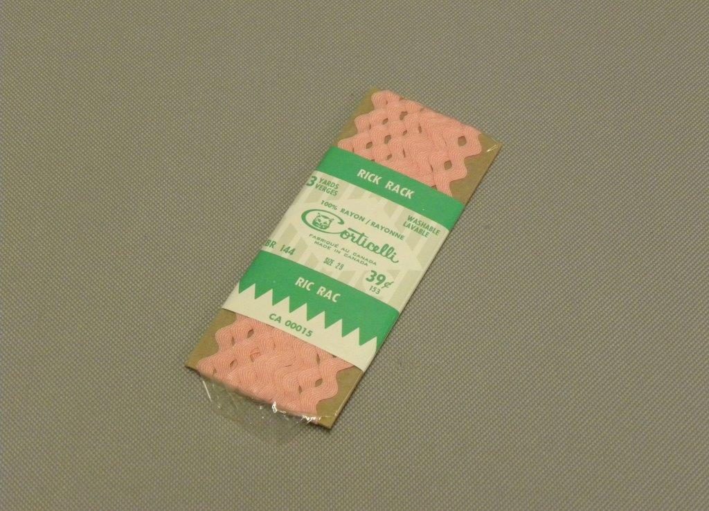 Colour photograph of a package of pink ribbons with a large grey-white and green label that describes the product.